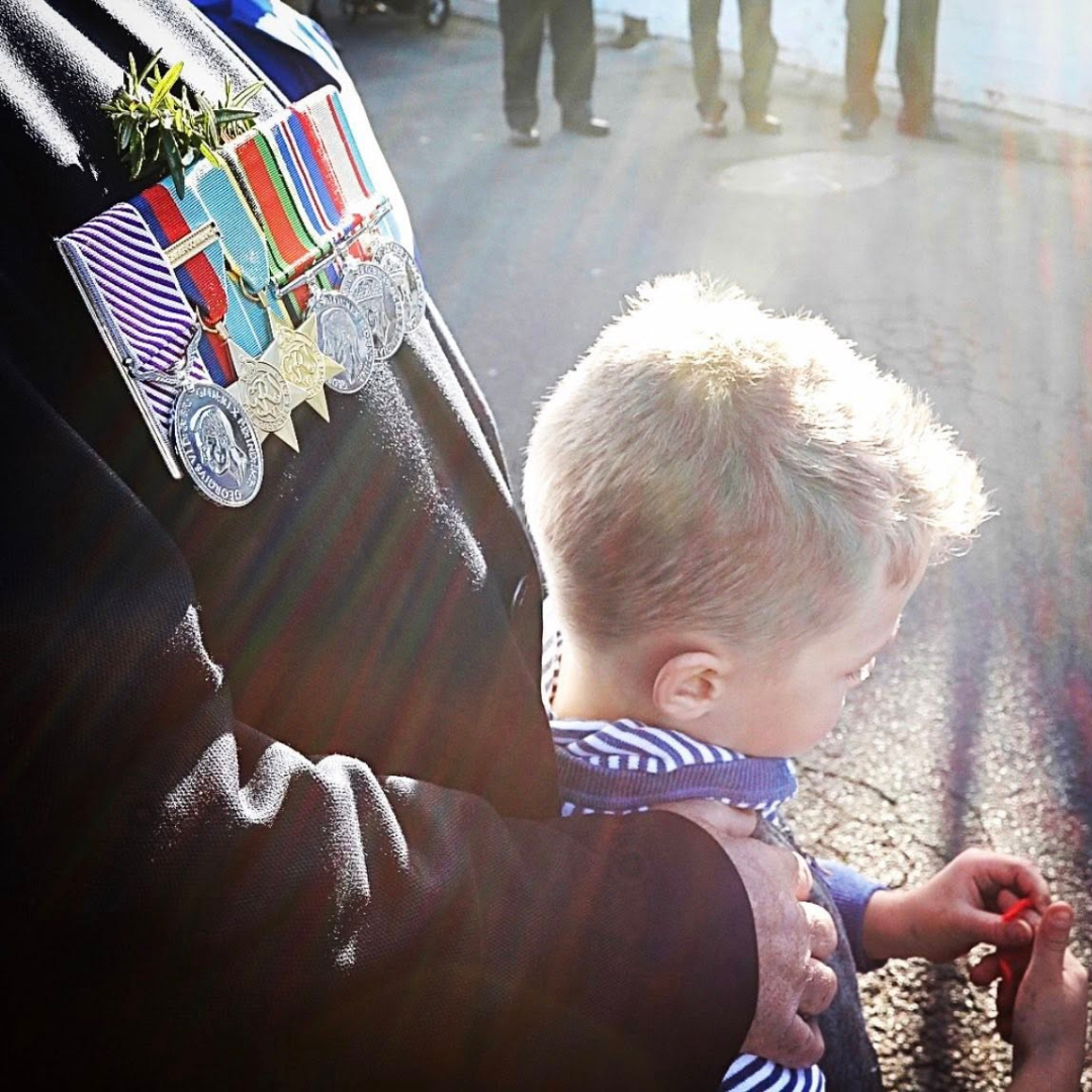 Children attending an Anzac Day service with their family, learning to remember and honour those who served.